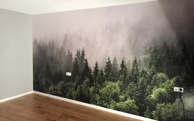Wand mit Fototapete eines nebligen Nadelwaldes in einem leeren Raum mit Holzboden.